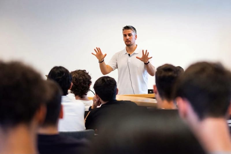 Tamas Piros teaching a full room, standing at the front and explaining with both hands